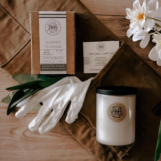 Finely Crafted Begonia & Bench Candles next to a white cotton glove