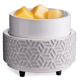 The Classic 2-in-1 Candle Warmer is a stylish white ceramic warmer with a geometric patterned base and black feet, ideal for both warming butter and candles. It accommodates a smaller white bowl designed to hold square yellow butter cubes, featuring an elegant textured interlocking hexagonal motif that enhances any setting.