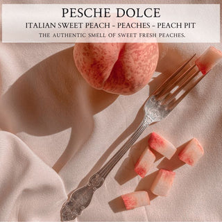 A sliced peach and a vintage fork rest on soft, beige fabric. The pink-hued slices mirror the whole peach in the background. Text above reads: "PESCHE DOLCE™ - 12oz Finely Crafted Scented Candle By Begonia & Bench®: Savor the authentic aroma of peaches with a hint of peach pit sweetness.