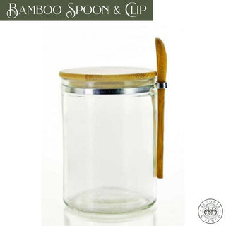 Introducing the Bamboo Spoon & Clip: A crystal-clear glass jar with an elegant silver rim and a natural bamboo lid. The jar features a bamboo spoon conveniently attached to its side with a secure clip, making it ideal for holding your favorite fall candle. "Bamboo Spoon & Clip" is prominently displayed in the top left corner, while "Iconic Houseware" along with its logo adorns the bottom right corner.