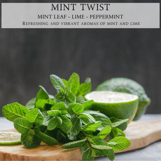 A bunch of fresh mint leaves and a halved lime placed on a wooden surface. In the background, there is a whole lime and some lime slices. Above them, text reads "Mint Twist™: Mint Leaf - Lime - Peppermint." Refreshing and vibrant aromas perfect for your fall candle collection by Begonia & Bench® in an elegant 12oz finely crafted scented candle.