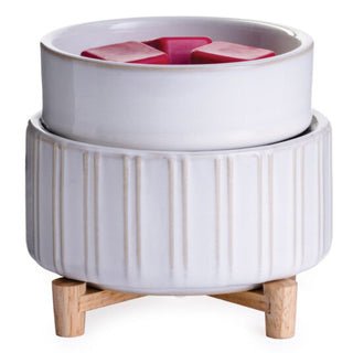 A Classic 2-in-1 Candle Warmer, featuring a glossy white ceramic fondue pot with vertical ridges, rests elegantly on a natural wooden stand. Inside the fondue pot is a removable bowl containing four red heart-shaped pieces, possibly meant for chocolate or cheese.