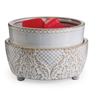 Introducing the Classic 2-in-1 Candle Warmer: a decorative wax warmer with a white ceramic bowl resting elegantly on an ornate base adorned with a gold, intricate pattern. The bowl accommodates two red fragrance wax melts, blending elegance and functionality for a stylish home decor piece perfect for adding aromatic charm.