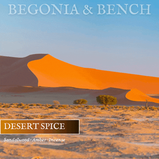An image showcases expansive orange sand dunes beneath a clear sky, with desert vegetation in the foreground. The text "BEGONIA & BENCH®" is displayed at the top. At the bottom, a brown box features the words "DESERT SPICE™," with "Sandalwood-Amber-Incense" written underneath. Ideal for creating a cozy fall candle ambiance, this product is Desert Spice™ - 9oz. Amber Jar Candle by Begonia & Bench®.
