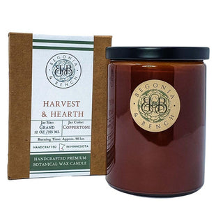 A Handcrafted in Minnesota fall candle with a coppertone glass jar and a round beige label reading "Begonia Bench." It comes packaged in a matching brown box with the same "Harvest & Hearth™" label. The GRAND 12 oz / 355 ml candle boasts an approximate burning time of 90 hours.