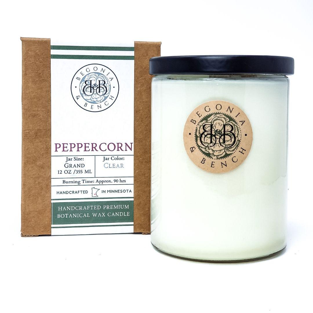 The Peppercorn - 12oz Finely Crafted Scented Candle By Begonia & Bench® is a white jar candle with a black lid and a brown tag featuring a black logo. The candle, handcrafted in Minnesota, offers the "Peppercorn" scent and burns for approximately 90 hours. It is noted as a premium botanical wax fall candle.