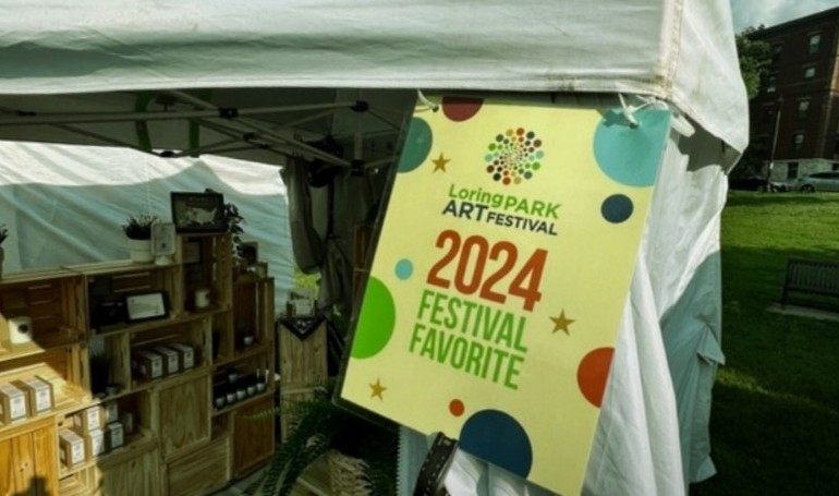 Our tent at the Loring Park Art Festival, wooden crates of boxed candles, and the 2024 Festival Favorite sign